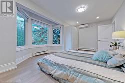 Bedroom featuring light hardwood / wood-style flooring, multiple windows, and a baseboard heating unit - 