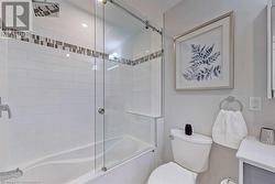 Bathroom with toilet and combined bath / shower with glass door - 