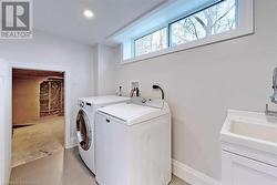 Clothes washing area featuring washing machine and clothes dryer, sink, and light tile patterned floors - 