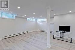 Basement featuring a baseboard radiator and light hardwood / wood-style floors - 