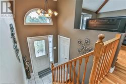 Foyer with vaulted ceiling with beams, a notable chandelier, and light wood-type flooring - 