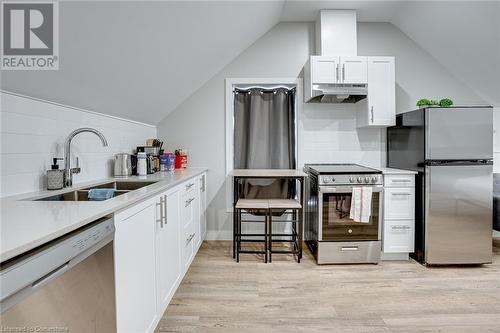 Kitchen with sink, light hardwood / wood-style flooring, vaulted ceiling, decorative backsplash, and appliances with stainless steel finishes - 102 Wellington Street N Unit# 4, Hamilton, ON - Indoor Photo Showing Kitchen With Double Sink With Upgraded Kitchen