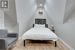 Bedroom featuring electric panel, wood-type flooring, and vaulted ceiling - 