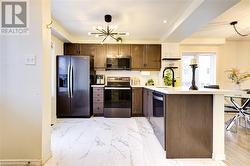 Kitchen featuring an inviting chandelier, a kitchen breakfast bar, sink, appliances with stainless steel finishes, and dark brown cabinetry - 