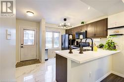 Kitchen with an inviting chandelier, sink, appliances with stainless steel finishes, dark brown cabinets, and kitchen peninsula - 