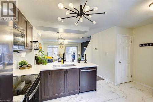 Kitchen with appliances with stainless steel finishes, dark brown cabinets, sink, a notable chandelier, and hanging light fixtures - 350 Dundas Street S Unit# 30, Cambridge, ON - Indoor