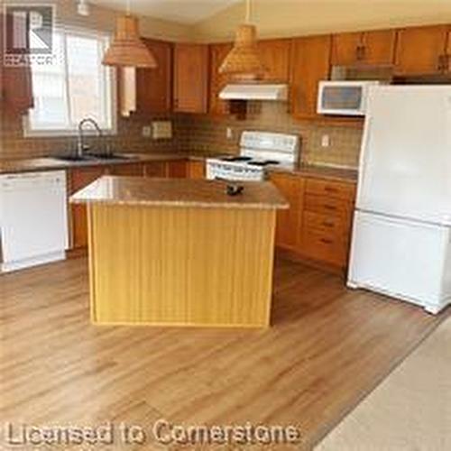 Kitchen with a center island, hanging light fixtures, white appliances, and light hardwood / wood-style flooring - 17 Hawkswood Drive, Kitchener, ON - Indoor Photo Showing Kitchen