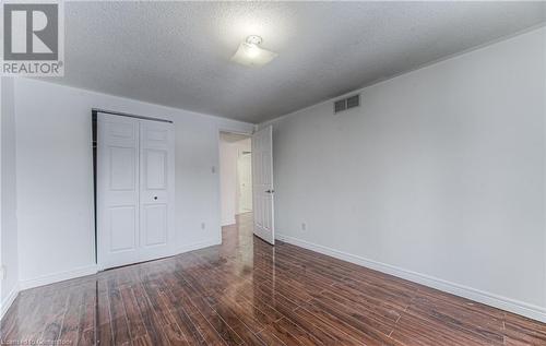 Unfurnished bedroom featuring dark hardwood / wood-style floors, a textured ceiling, and a closet - 21 Woodborough Place, Cambridge, ON - Indoor Photo Showing Other Room