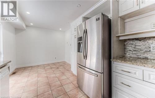 Kitchen featuring backsplash, light stone counters, white cabinets, and stainless steel refrigerator with ice dispenser - 21 Woodborough Place, Cambridge, ON - Indoor