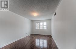 Unfurnished room with dark wood-type flooring and a textured ceiling - 