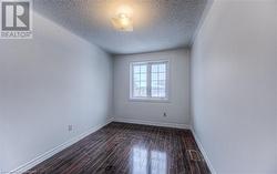 Empty room featuring a textured ceiling and dark hardwood / wood-style floors - 