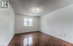 Unfurnished room with a textured ceiling and dark wood-type flooring - 