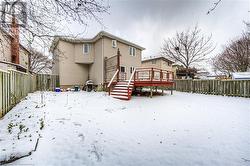 Snow covered rear of property with a wooden deck - 