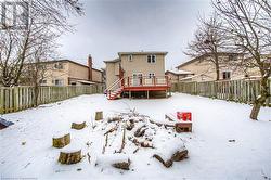 Snow covered back of property featuring a wooden deck - 