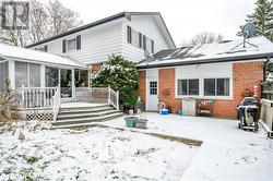 Snow covered back of property with a deck and a sunroom - 