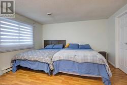 Bedroom with hardwood / wood-style floors, a textured ceiling, and a baseboard radiator - 