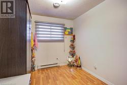 Empty room with a textured ceiling, light hardwood / wood-style flooring, and baseboard heating - 