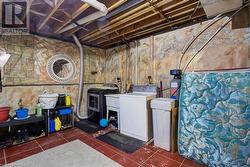 Clothes washing area with washer and dryer and dark tile patterned flooring - 