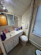 Bathroom featuring vaulted ceiling, a baseboard radiator, toilet, and tile walls - 