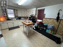 Kitchen with black electric range oven, white cabinetry, sink, and exhaust hood - 