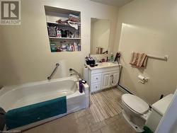 Bathroom featuring a bathing tub, vanity, a baseboard heating unit, and toilet - 