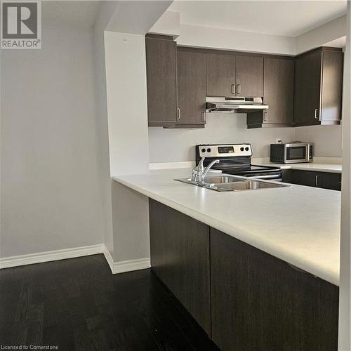 Kitchen featuring stove, dark brown cabinets, sink, exhaust hood, and wood-type flooring - 39 Appleby Street, Kitchener, ON - Indoor Photo Showing Kitchen With Double Sink