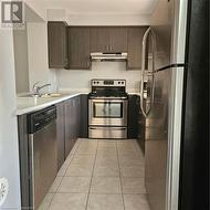 Kitchen featuring ventilation hood, light tile patterned floors, stainless steel range oven, dishwasher, and fridge - 