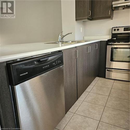 Kitchen featuring sink, extractor fan, dishwashing machine, dark brown cabinets, and range - 39 Appleby Street, Kitchener, ON - Indoor Photo Showing Kitchen With Stainless Steel Kitchen With Double Sink