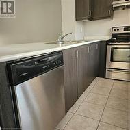 Kitchen featuring sink, extractor fan, dishwashing machine, dark brown cabinets, and range - 