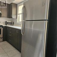 Kitchen with stainless steel refrigerator, light tile patterned floors, and range - 