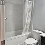 Full bathroom featuring vanity, shower / bath combo, and toilet - 