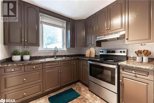 Kitchen featuring electric range, backsplash, dark stone countertops, and sink - 90 East 11Th Street, Hamilton, ON - Indoor Photo Showing Kitchen With Double Sink