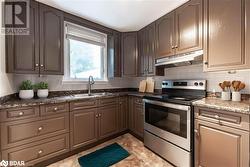 Kitchen featuring electric range, backsplash, dark stone countertops, and sink - 