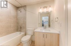 Full bathroom with hardwood / wood-style flooring, vanity, tiled shower / bath combo, and toilet - 