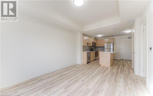 Kitchen with a center island, stainless steel appliances, a raised ceiling, backsplash, and light hardwood / wood-style floors - 301 Westmount Road W Unit# 204, Kitchener, ON - Indoor Photo Showing Kitchen