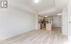 Kitchen with a center island, stainless steel appliances, a raised ceiling, backsplash, and light hardwood / wood-style floors - 