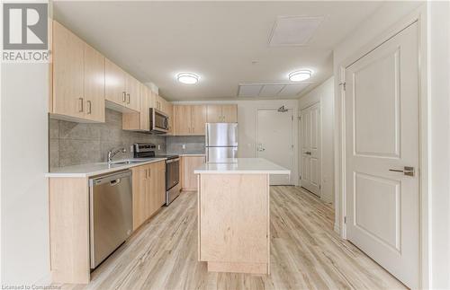 Kitchen with light wood-type flooring, light brown cabinets, a center island, and stainless steel appliances - 301 Westmount Road W Unit# 204, Kitchener, ON - Indoor Photo Showing Kitchen