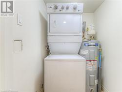 Laundry area with water heater and stacked washer and clothes dryer - 