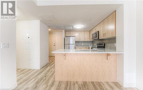 Kitchen featuring a kitchen breakfast bar, light hardwood / wood-style flooring, light brown cabinetry, appliances with stainless steel finishes, and kitchen peninsula - 301 Westmount Road W Unit# G1, Kitchener, ON - Indoor Photo Showing Kitchen