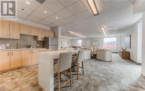 Kitchen with stainless steel fridge, a kitchen island, a kitchen bar, and light brown cabinetry - 301 Westmount Road W Unit# G1, Kitchener, ON - Indoor