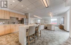 Kitchen with stainless steel fridge, a kitchen island, a kitchen bar, and light brown cabinetry - 