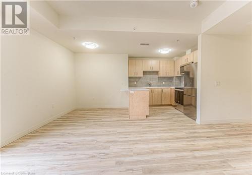 Kitchen with backsplash, light brown cabinetry, light hardwood / wood-style floors, and stainless steel appliances - 301 Westmount Road W Unit# 414, Kitchener, ON - Indoor Photo Showing Kitchen