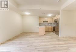 Kitchen with backsplash, light brown cabinetry, light hardwood / wood-style floors, and stainless steel appliances - 