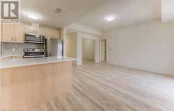 Kitchen featuring light brown cabinets, kitchen peninsula, stainless steel appliances, and light hardwood / wood-style flooring - 