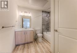 Full bathroom with hardwood / wood-style floors, vanity, tiled shower / bath combo, and toilet - 