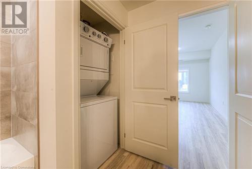 Laundry room featuring stacked washer / dryer and light hardwood / wood-style flooring - 301 Westmount Road W Unit# 414, Kitchener, ON - Indoor Photo Showing Laundry Room