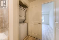 Laundry room featuring stacked washer / dryer and light hardwood / wood-style flooring - 