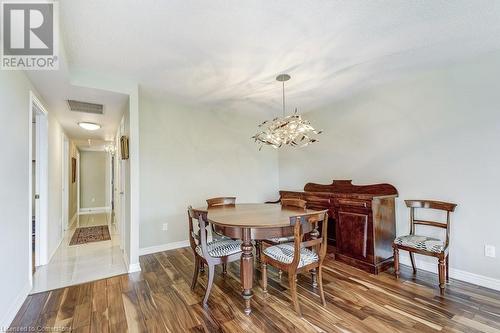 Dining room featuring an inviting chandelier, a textured ceiling, and hardwood / wood-style flooring - 77 Governors Road Unit# 501, Dundas, ON - Indoor Photo Showing Dining Room