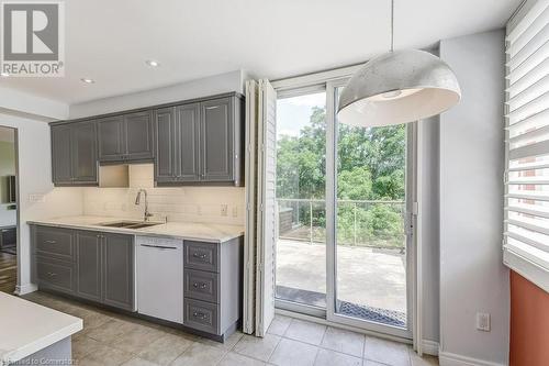 Kitchen featuring backsplash, gray cabinetry, white dishwasher, sink, and decorative light fixtures - 77 Governors Road Unit# 501, Dundas, ON - Indoor Photo Showing Kitchen With Double Sink