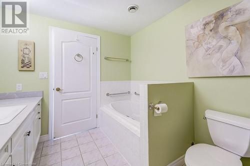 Bathroom with tile patterned flooring, a relaxing tiled tub, toilet, and vanity - 77 Governors Road Unit# 501, Dundas, ON - Indoor Photo Showing Bathroom